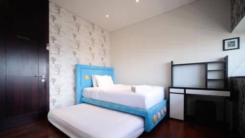 a small bedroom with two beds and a tv at Spacious and Restful 2BR at Sumatra36 Apartment By Travelio in Surabaya