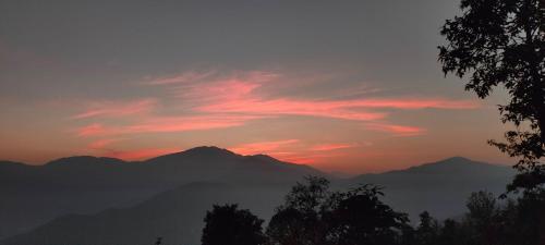 a sunset with mountains in the background and a tree at Into the mountain in Pokhara