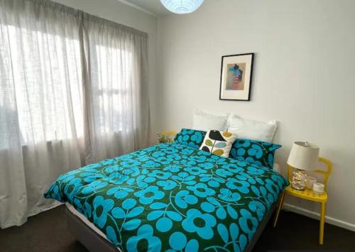 a bedroom with a bed with a blue comforter at 10 Nikau Place in Christchurch