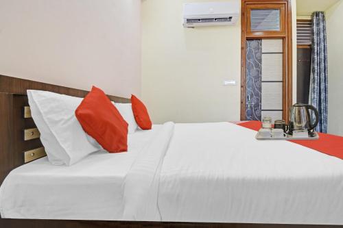 a bedroom with a white bed with red and white pillows at Hotel O Kalot in Jaipur