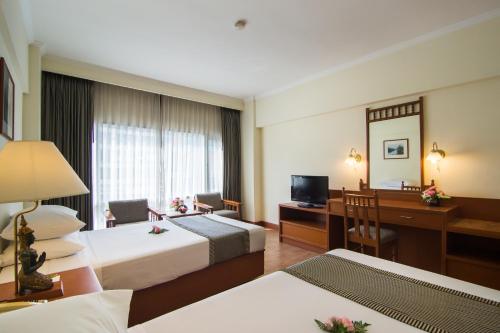 a hotel room with two beds and a desk at Bangkok Palace Hotel in Bangkok