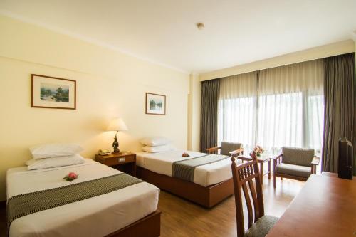 a hotel room with two beds and a table at Bangkok Palace Hotel in Bangkok