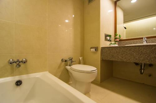 a bathroom with a tub and a toilet and a sink at Bangkok Palace Hotel in Bangkok