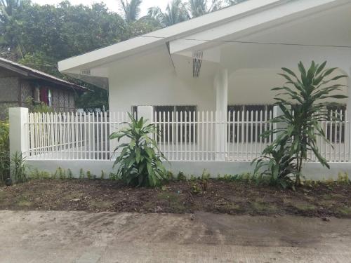 a white fence in front of a white house at Luna Oslob Travellers Inn in Oslob