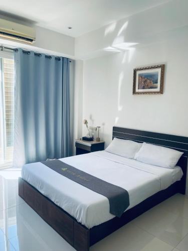 a bedroom with a large bed with blue curtains at Vera Hotel in Angeles