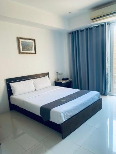 a bedroom with a large bed with blue curtains at Vera Hotel in Angeles