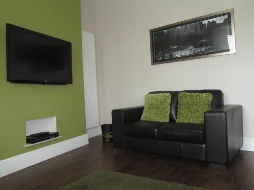 a living room with a couch and a flat screen tv at Geminian in Harrogate