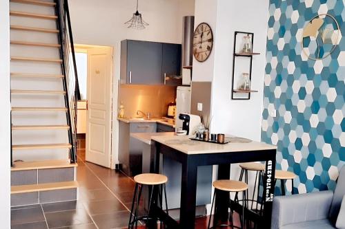 une cuisine avec une table et des tabourets dans une pièce dans l'établissement Appartement cocooning à Raismes - 48 m² - Idéal pour 4 personnes, à Raismes