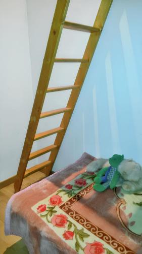 un oiseau jouet assis sur un oreiller à côté d'une échelle dans l'établissement Maison charmante à Coucouron, vue montagne, cheminée, à Coucouron