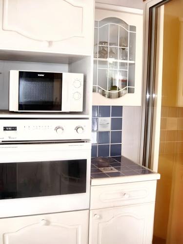 une cuisine avec des armoires blanches et un micro-ondes dans l'établissement Maison accueillante à Noirmoutier-en-l'Île 45 m² avec jardin privé, à Noirmoutier-en-l'lle