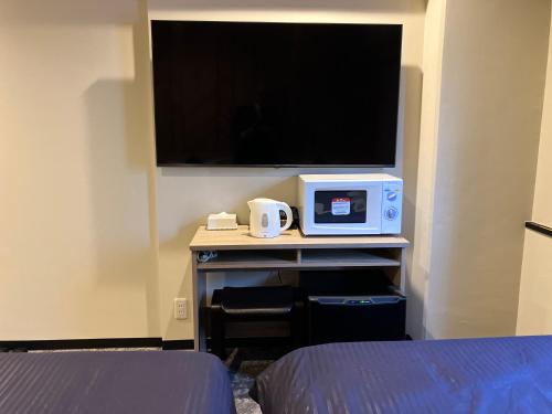 a room with a tv and a table with a microwave at HOTEL LiVEMAX BUDGET Naha in Naha