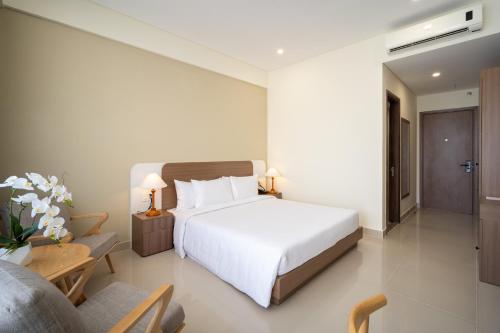 a bedroom with a white bed and a chair and a couch at The HUB Hotel - Airport in Ho Chi Minh City