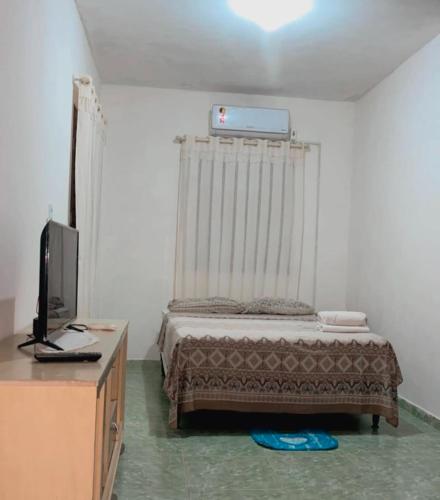 a bedroom with a bed and a desk with a television at Chalé R&M in Aracati