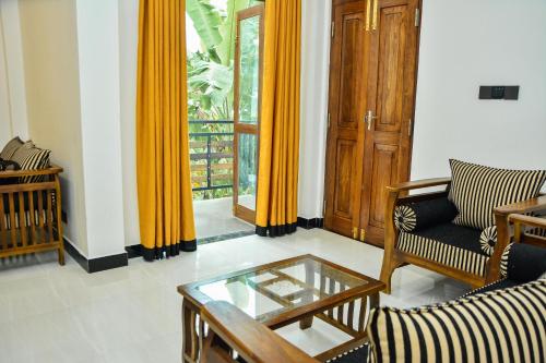 a living room with yellow curtains and a glass table at Ocean Bliss Villa Mirissa in Kamburugamuwa