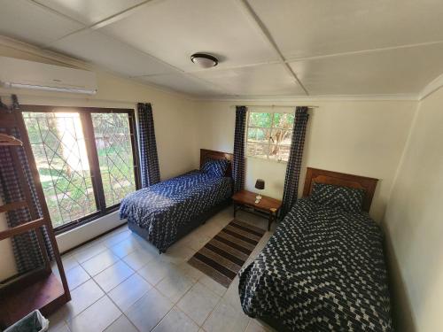a bedroom with two beds and a window at Mkumbi Farm Cottage in Hluhluwe