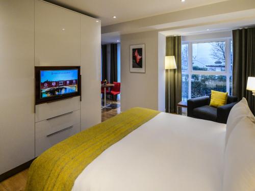 a hotel room with a bed and a flat screen tv at PREMIER SUITES Dublin, Ballsbridge in Dublin