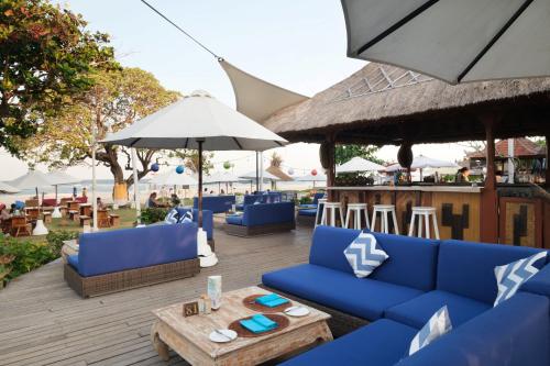 a patio with blue couches and tables and umbrellas at Ayodya Resort Bali in Nusa Dua