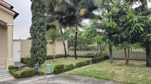a yard with palm trees and a fence at Casa Moderna con Piscina y Espacios al Aire Libre en Ciudad Celeste, Samborondón in Barranco