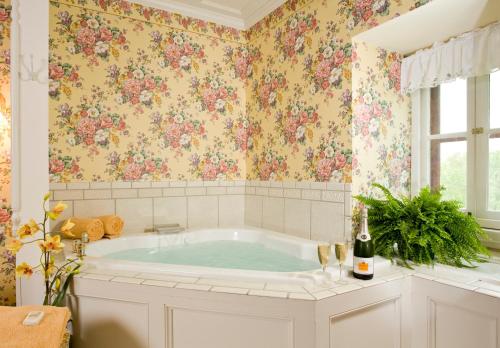 a bathroom with a tub with floral wallpaper at Garth Woodside Mansion Bed and Breakfast in Hannibal