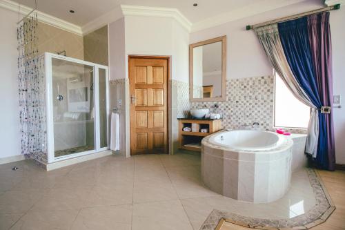a large bathroom with a tub and a shower at Castellon Boutique Hotel in Table View