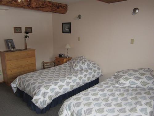 a bedroom with two beds and a dresser at Smithers Driftwood Lodge in Smithers