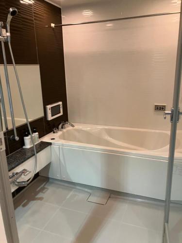 a bath tub in a bathroom with a mirror at HOTEL LiVEMAX BUDGET Naha in Naha