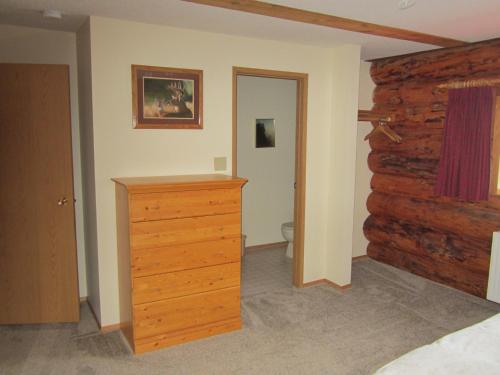 a bedroom with a dresser and a log wall at Smithers Driftwood Lodge in Smithers