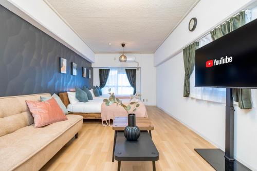 a living room with a couch and a tv at Lions Mansion Shin-Osaka in Osaka
