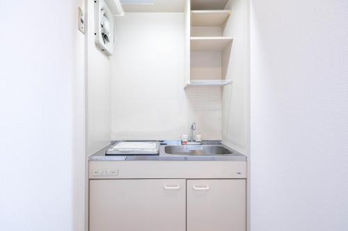 a small kitchen with a sink in a room at Lions Mansion Shin-Osaka in Osaka