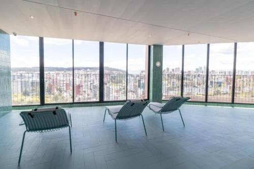 une chambre avec trois chaises dans un bâtiment avec fenêtres dans l'établissement Departamento Epic-Quito, à Hacienda Carolina