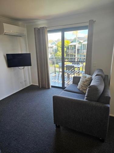 a living room with a couch and a tv and a balcony at Noosa Lakes Resort in Noosaville