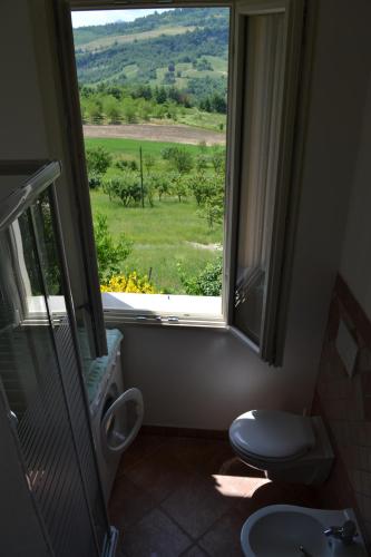 a bathroom with a toilet and a window with a view at Nido D'Ape bed and breakfast in  Montepetra 