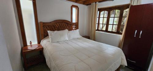 a bedroom with a bed with a wooden headboard and a window at Alta Vista de Cahuil in Pichilemu