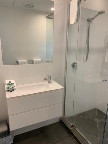 a white bathroom with a shower and a sink at Noosa Lakes Resort in Noosaville