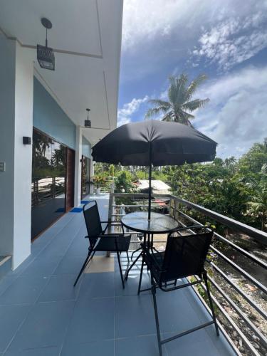 een balkon met een tafel en stoelen en een parasol bij A-rena Homestay in General Luna