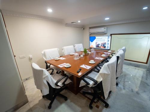 a conference room with a wooden table and white chairs at Hotel Pravasa Stay in Vadodara