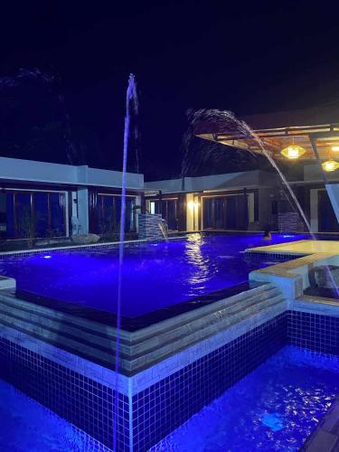 a swimming pool at night with a fountain at Bluewaves Hostel & Villa Panagsama by Hiverooms in Moalboal