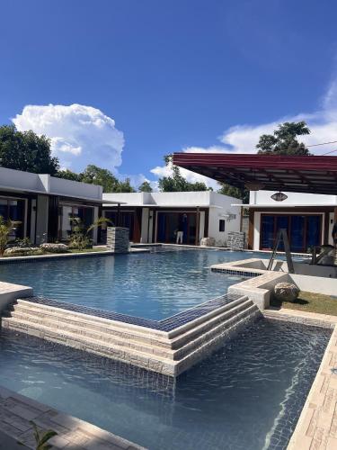 a swimming pool with stairs in front of a house at Bluewaves Hostel & Villa Panagsama by Hiverooms in Moalboal