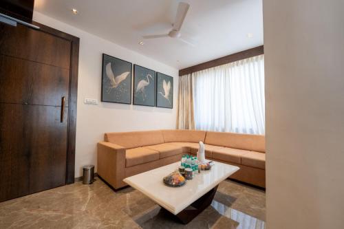 a living room with a couch and a table at Ramee Tarang Hotel Indore in Indore