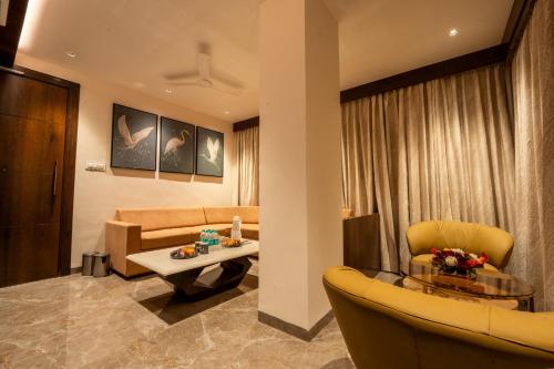 a living room with a couch and a table and chairs at Ramee Tarang Hotel Indore in Indore