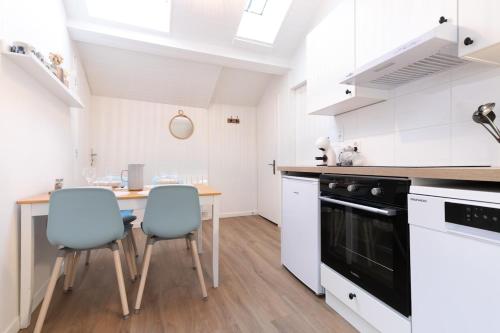 a kitchen with white cabinets and a wooden table and chairs at Au Petit Sommet - Cerf Brun Appartement centre ville 35M2 in Modane
