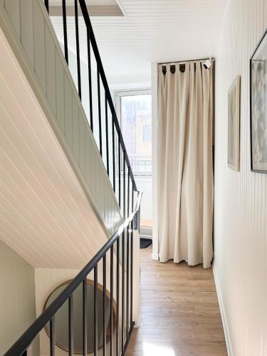 a hallway with a staircase and a window at Au Petit Sommet - Cerf Brun Appartement centre ville 35M2 in Modane