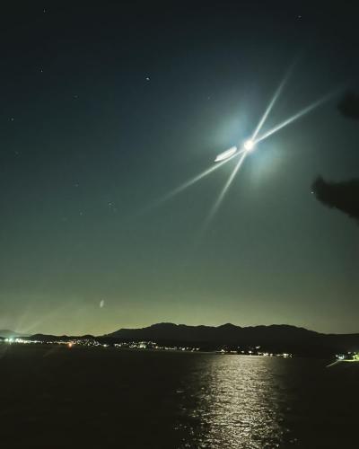 a bright light in the sky over the water at night at ペンションレークサイド in Otsu