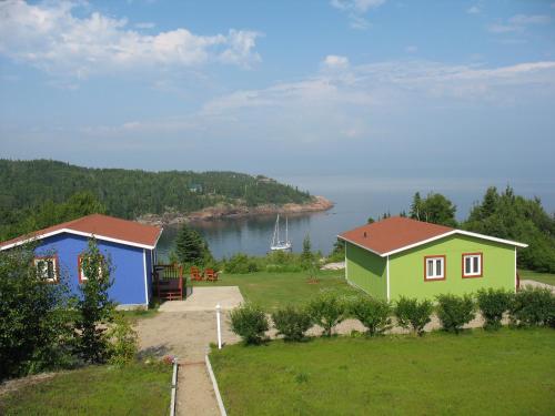 two houses on a field with a view of the water at Les Chalets au Bord de la Mer in Les Escoumins