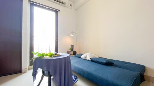 a bedroom with a blue bed and a table at Comfort Living 2BR at Transpark Cibubur Apartment By Travelio in Depok