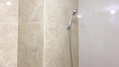 a shower with a shower head in a bathroom at Comfort Living 2BR at Transpark Cibubur Apartment By Travelio in Depok