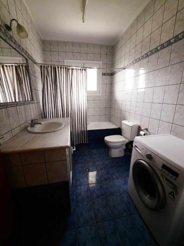 a bathroom with a toilet sink and a washing machine at Enjoy Inn in Néa Karváli