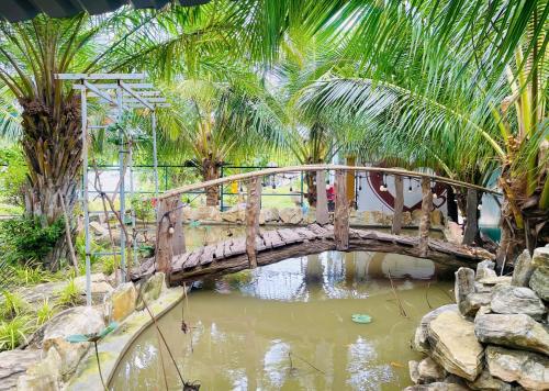 a wooden bridge over a pond in a garden at The Lana Ho Tram Homestay in Xuyên Mộc
