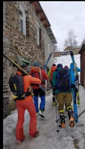 a group of people with backpacks and skis walking down a street at Chvibiani Guesthouse & Bar in Ushguli