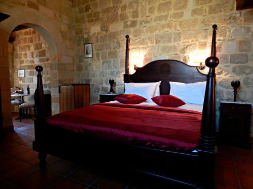 a bedroom with a large bed with red sheets and pillows at S.Nikolis' Historic Boutique Hotel in Rhodes Town
